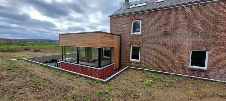 Maison en briques rouges et annexe au bardage en bois, terrasse en gravier devant