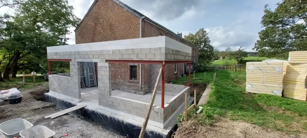 Annexe en blocs de béton avec poutres métalliques rouges, en construction