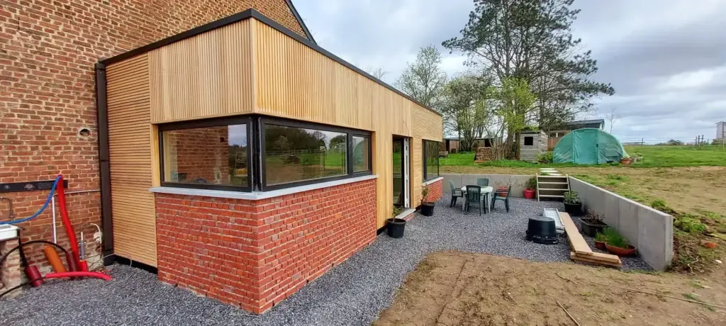 Annexe au bardage en bois et soubassement en briques rouges, terrasse en gravier